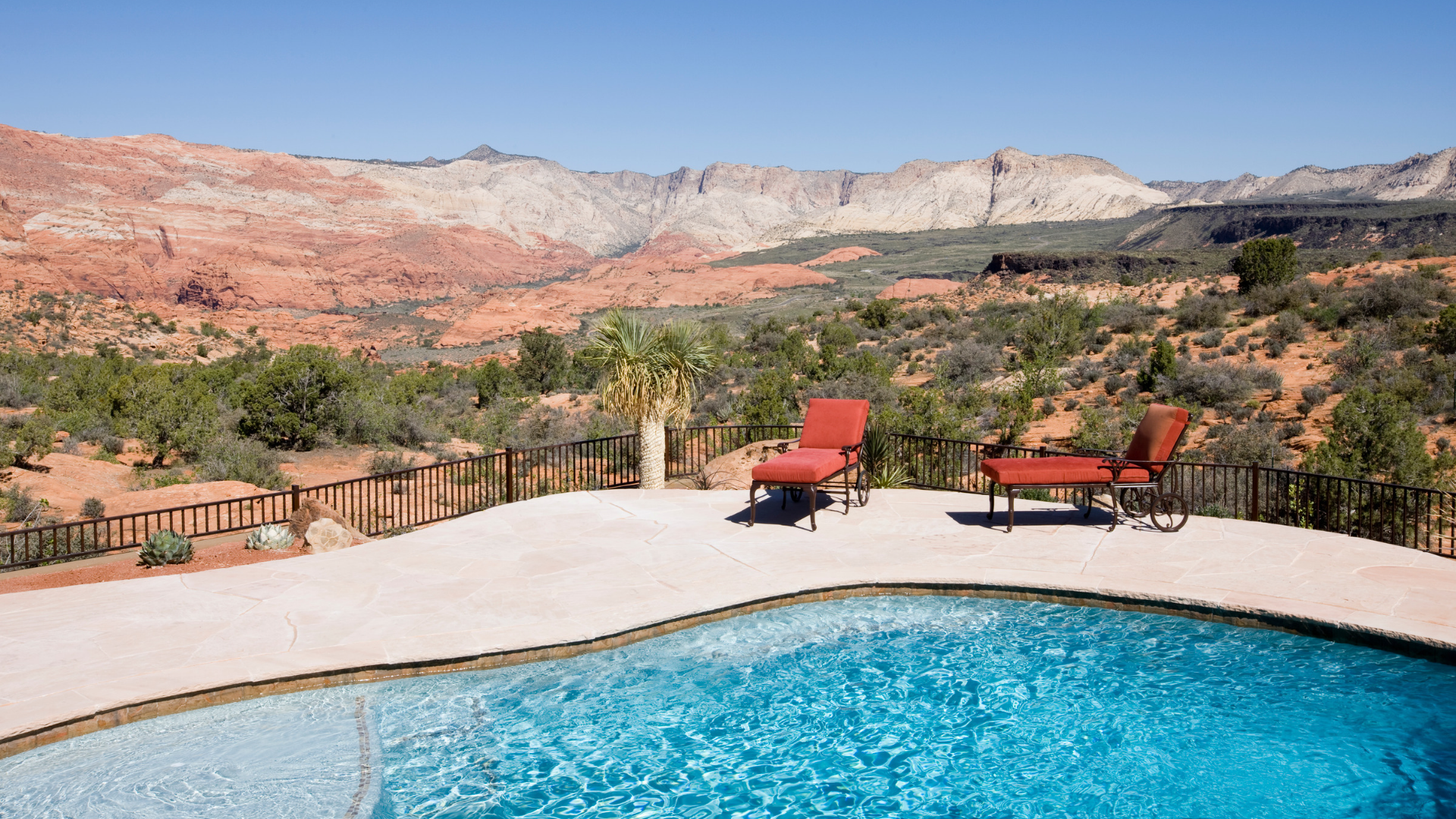 Blue backyard pool overlooking red-rock desert scenery